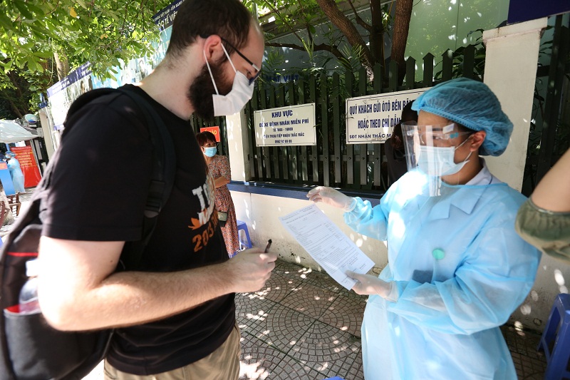  Nhân viên y tế hướng dẫn anh Robert thực hiện khai giấy đăng ký tiêm vaccine